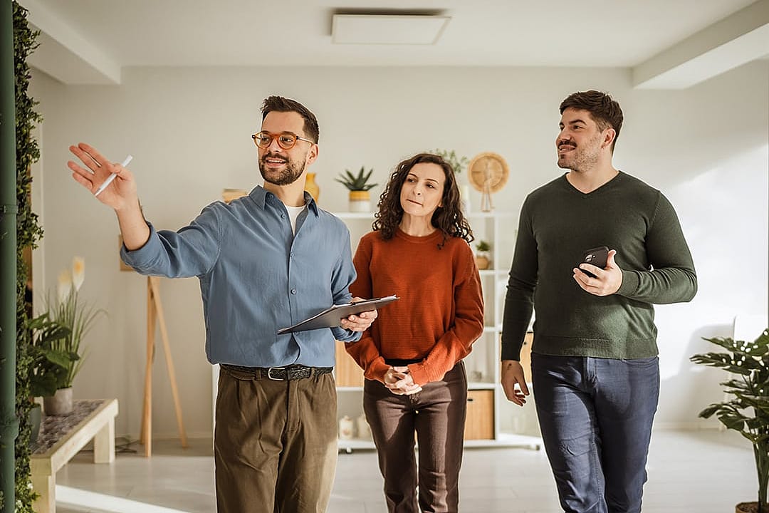 Real estate agent guiding a young couple through a new modern apartment.